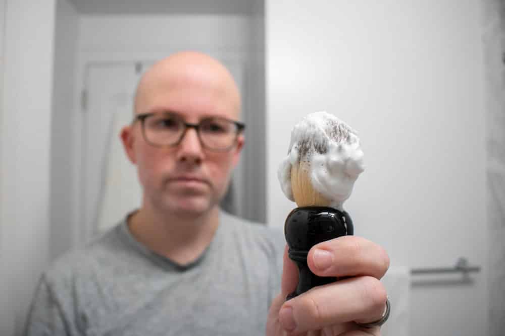 man holding a shaving brush loaded with cella shave cream