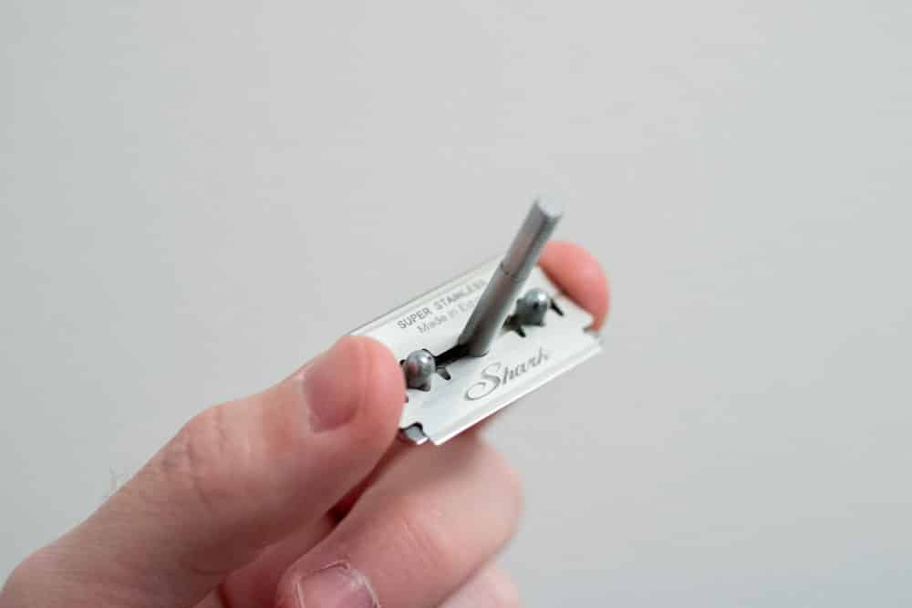 hand holding razor cap with single razor blade loaded